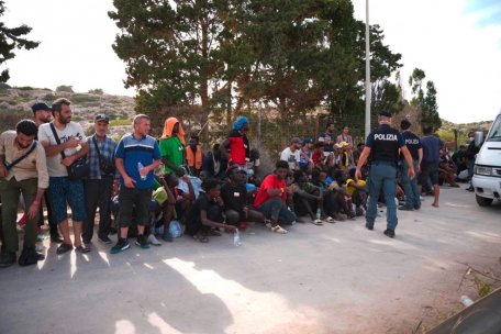 Italienische Polizisten „bewachen“ Neuankömmlinge im Hafen von Lampedusa