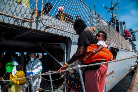 Migrantinnen besteigen im Hafen von Lampedusa ein italienisches Militärschiff, mit dem sie nach Sizilien gebracht werden