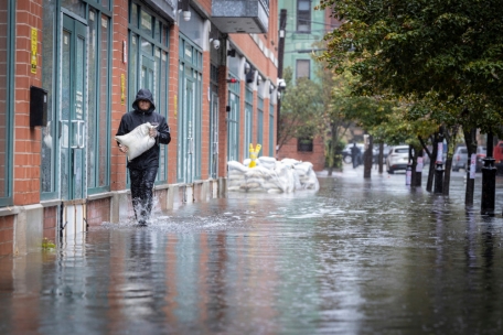 Eine Person trägt Sandsäcke, während schwere Regenfälle die Straßen in New York überfluten