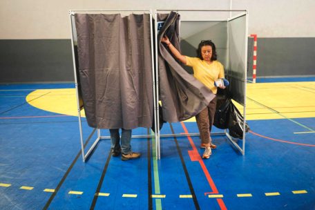 Une femme sort de l'isoloir avant de voter dans un bureau de vote situé dans un gymnase