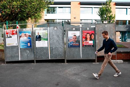 Un électeur passe devant des affiches électorales pour les élections législatives françaises à Hénin-Beaumont, dans le nord de la France